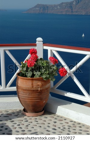 santorini greek islands stone patio with geraniums and sailboat in sea