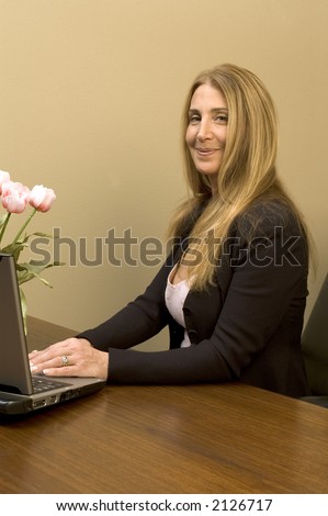 female executive at desk in office with computer and flowers