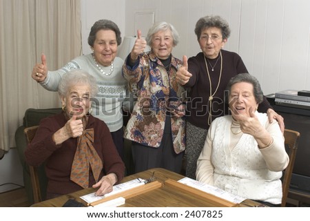 group of happy senior women playing mah-jong with friends thumbs up positive sign