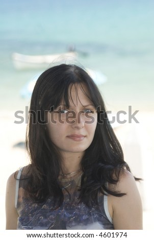 attractive young woman with slight smile beach and boats in background