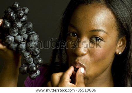 portrait of smiling happy pretty sexy young latin puerto rican black  woman eating healthy food fresh fruit grapes