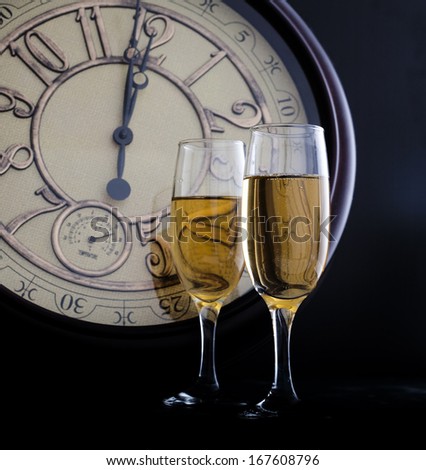 New Year's at midnight with champagne glasses and clock on light background