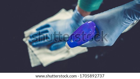 surface home cleaning spraying antibacterial sanitizing spray bottle disinfecting against COVID-19 spreading wearing medical blue gloves. Sanitize surfaces prevention in hospitals and public spaces.