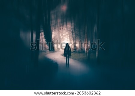 Horror background of a ghostly figure in enchanted a forest on a moody, foggy night. Halloween concept