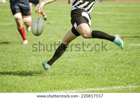Rugby player legs kicking the oval ball