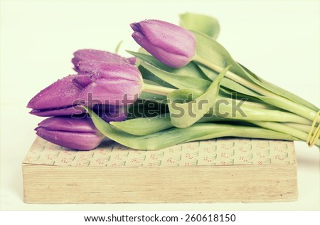 Old book and purple tulips. Retro style toned picture