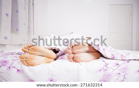 Feet of a couple sleeping side by side.
