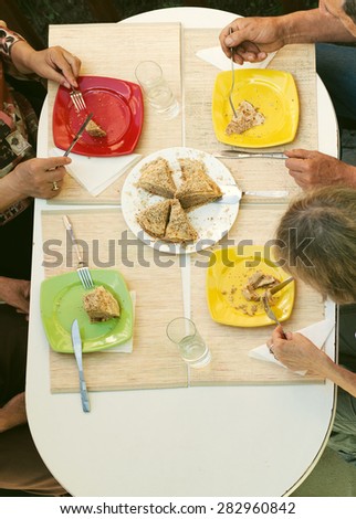 Middle aged friends eating desert outside - top view