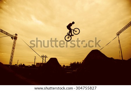 Silhouette of a man doing a jump with a bmx bike against sunset sky