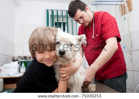 Little boy holding his Westie while the veterinarian is preparing to give a vaccine