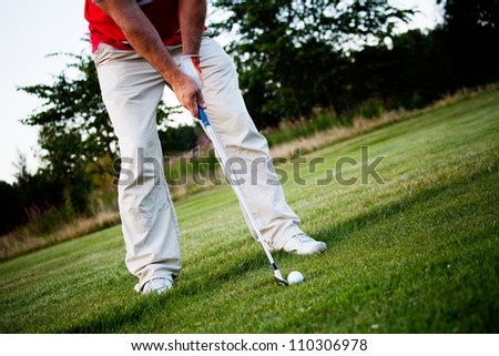 Male golfer shooting a golf ball from green grass