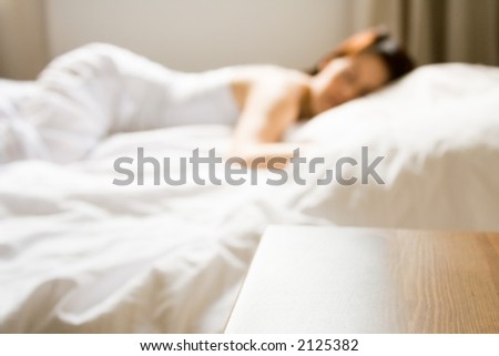 Young woman taking a nap in bedroom, focus on table in front