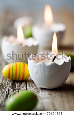 Easter candles on wooden table with egg decorations