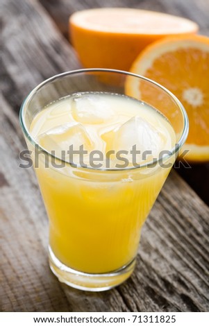 Glass of orange juice with ice cubes, selective focus