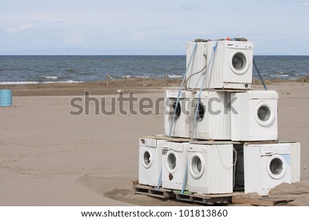 lot of old washing machines abandoned in the middle of a beach