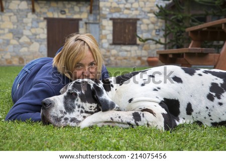 Woman with dog lying on the green grass in the park. great dane dog breed