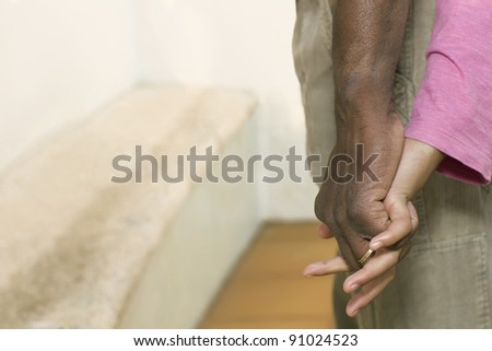 hand of an African man taking the hand of a white woman, expressing tenderness
