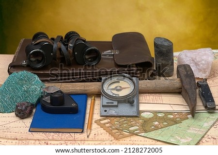Geological fieldwork tools: map case, geological hammer, compass, magnifying glass, pocket knife, binoculars, drill core, rock samples, topographic and geological maps Imagine de stoc © 