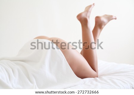 Nude woman with beautiful legs lying on bed