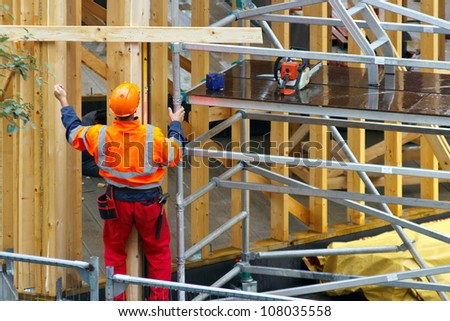 Construction worker in wooden house construction site