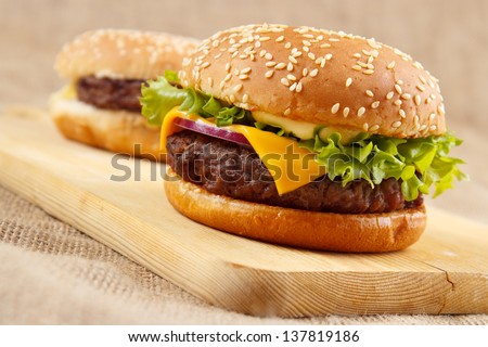 Two homemade grilled hamburgers on wooden board