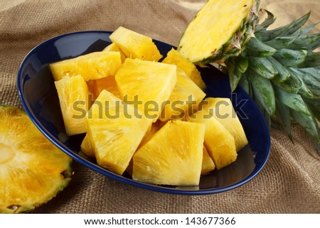 Cut pineapple on dish with green leaves closeup