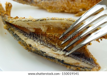 Cleaning cooked fish for eating with fork closeup