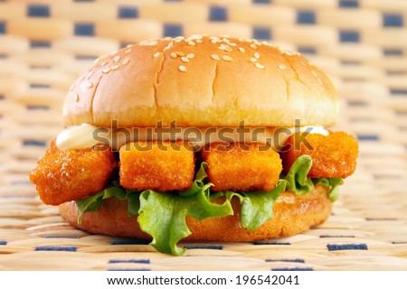 Fishburger with fish sticks and mayonnaise on table mat