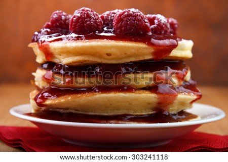 Warm baked pancakes with strawberry jam and fresh raspberry fruits on white plate