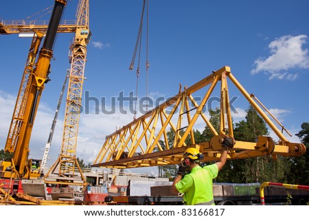 Setting up a tower crane in the construction site.  Workers are started to install the jib of the crane.
