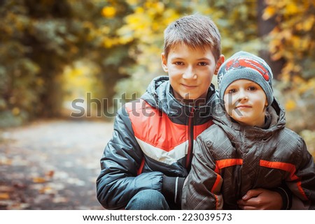 brothers walking with his four year old brother in the autumn park. Vertical view