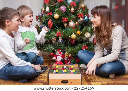 Happy mother and two her children playing near an decorated fir-tree for Christmas
