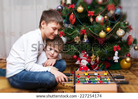 Happy brothers playing near an decorated fir-tree for Christmas