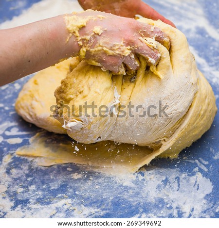 Woman\'s hands knead dough on blue table