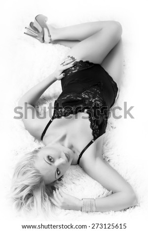 Black and white Soft Focus Photo of beautiful blonde girl lying on the carpet in black underwear