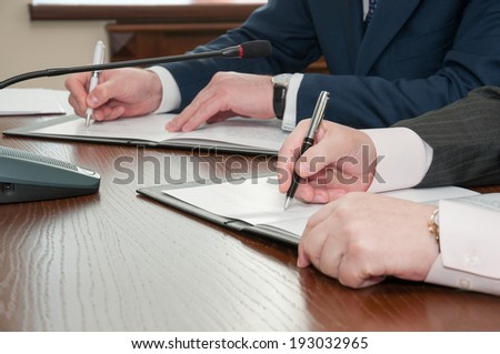 close up of two partners hands signing documents