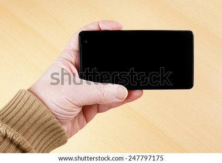 male hand holding mobile smart phone with blank display screen
