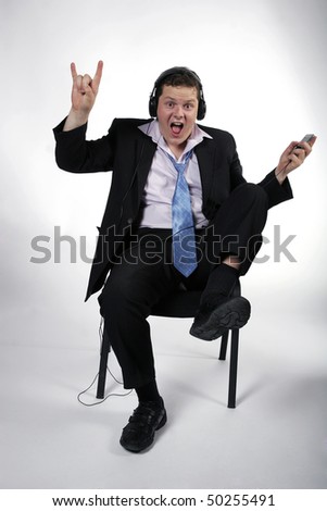 Young businessman having fun at work while listening to music. Studio shot