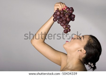 Part of photo series . Woman with red grapes. Studio shots