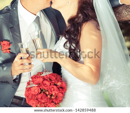 Wedding couple holding wine glasses and kissing