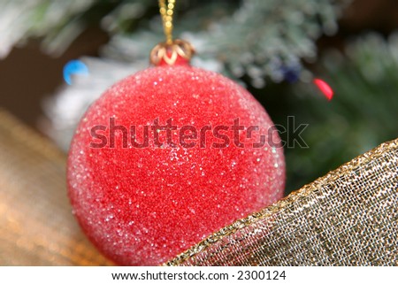christmas decorative red ball and ribbon with tree in background