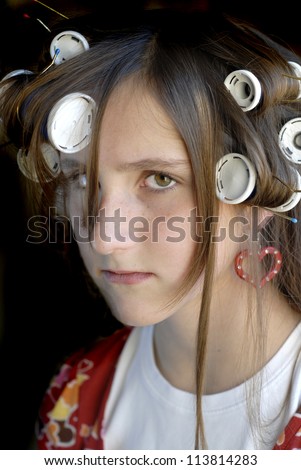 Young girl with freckles on face looking mean with curlers in hair
