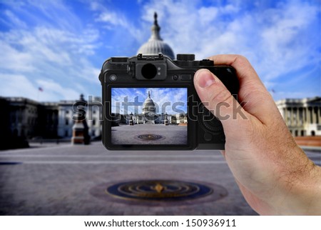 Hand holding camera taking photograph of US Capitol building by tourise