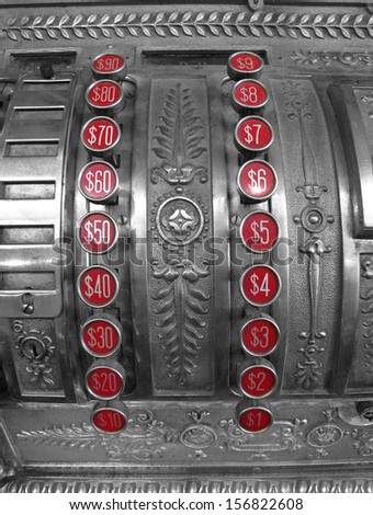 Detailed closeup of an old cash register with red number buttons for dollar amounts