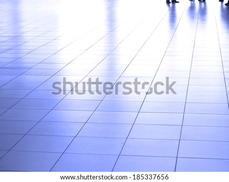 Several people walking across white marble tile floor