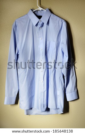 Detail of blue dress shirt hanging on hanger with light