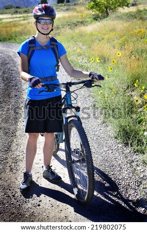 Detail of woman mountain biking wearing blue exercise shirt and helmet