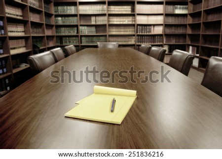 Conference room table with several leather chairs and shelves of books