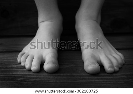 Detail of child bare feet black and white on wood steps