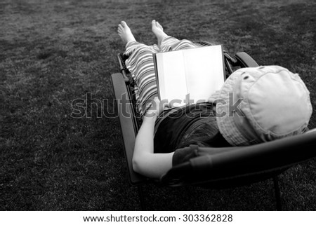 Photo of Person Lounging in Lawn Chair Relaxing and Reading Book